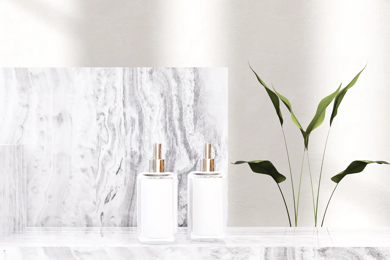 Two white bottles with gold accents and a plant